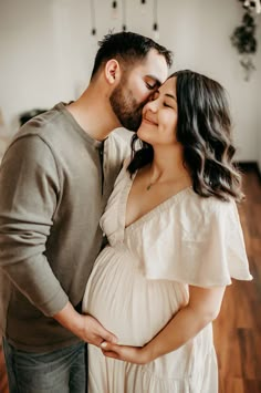 a pregnant couple kissing while standing next to each other