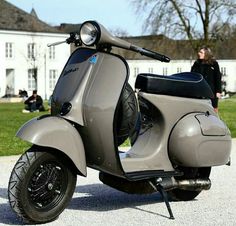 a scooter is parked in front of a building with people sitting on the lawn