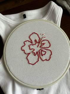 a white t - shirt with red embroidery on it