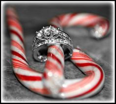 two wedding rings sitting on top of candy canes next to an engagement ring in the middle