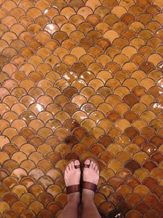 a person standing in front of a tiled floor with their bare feet on the ground