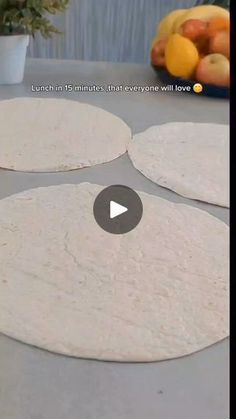 three uncooked tortillas sitting on top of a table next to fruit