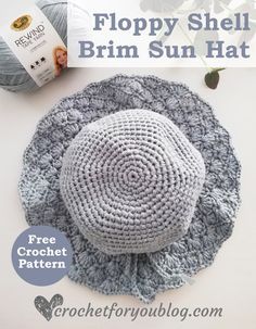 a crocheted hat sitting on top of a table next to yarn and flowers