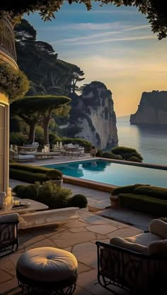 an outdoor swimming pool surrounded by greenery next to the ocean at sunset or dawn