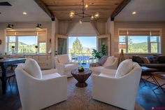 a living room filled with white furniture next to a wooden ceiling mounted flat screen tv