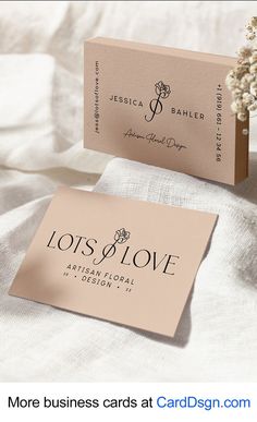 two business cards sitting next to each other on top of a white cloth covered bed