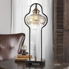 a lamp that is sitting on top of a table next to a brown leather chair