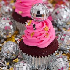 cupcakes with pink frosting and disco balls on the side, surrounded by confetti