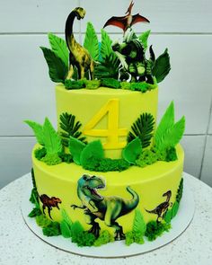 a three tiered cake decorated with dinosaurs and plants