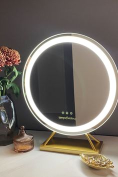 a round mirror sitting on top of a table next to a vase with flowers in it