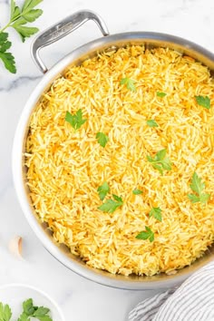 a pot filled with rice and parsley on top of a white marble countertop