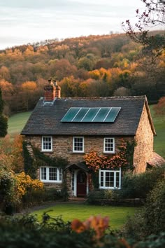 a brick house with a solar panel on the roof and windows in front of it