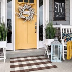 a yellow front door with two white chairs