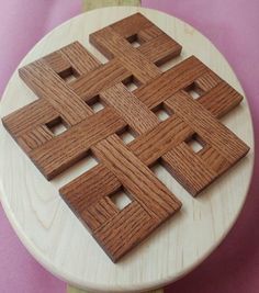 four wooden squares are arranged on top of a white plate with pink cloth behind them