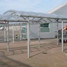 an empty parking lot with several cars parked in front of the building and one person pushing a cart behind it