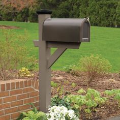 a mailbox sitting in the middle of a flower bed next to a brick wall