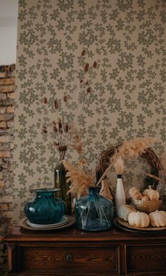 a table topped with vases filled with flowers and other items next to a wall paper