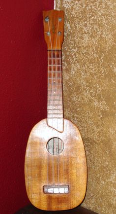 an old ukulele sitting on top of a table next to a red wall