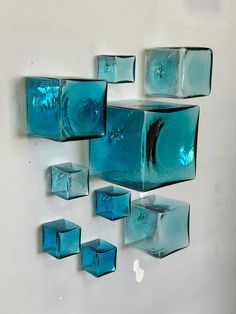 several blue glass cubes are hanging on the wall in front of a white wall