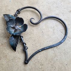 a heart shaped metal object with flowers on it's side and the word love spelled in black