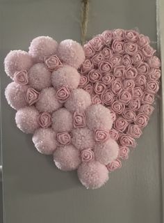 a heart made out of pink roses hanging on a wall