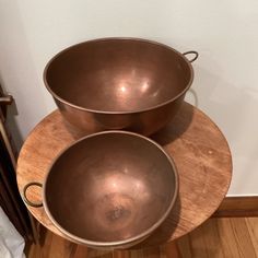 two metal bowls sitting on top of a wooden table