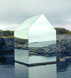 a large mirror sitting on top of a body of water next to a rocky shore