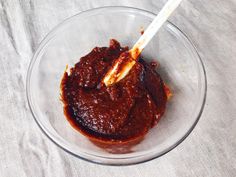 a glass bowl filled with sauce and a white spoon