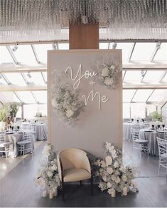 a chair sitting in front of a sign that says you and me with flowers on it