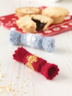 two small knitted objects on a table next to some cookies and other food items