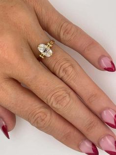 a woman's hand with red and pink manicured nails holding a diamond ring