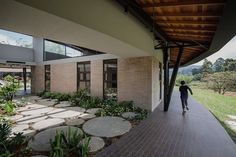 a person walking down a walkway next to a building with lots of plants on it