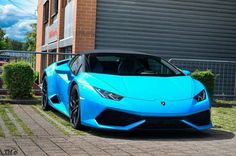 a blue sports car parked in front of a building