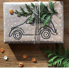 a present wrapped in brown paper with a car drawn on it and christmas decorations around it