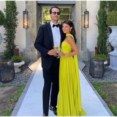 a man in a tuxedo standing next to a woman in a yellow dress