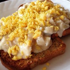 two pieces of bread topped with cream sauce and crumbs on a white plate