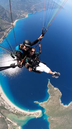 two people are parasailing over the water and land in front of an island