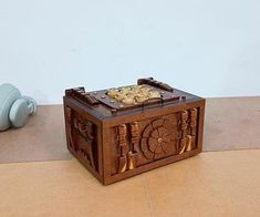 a small wooden box sitting on the floor next to a blue vase with flowers in it