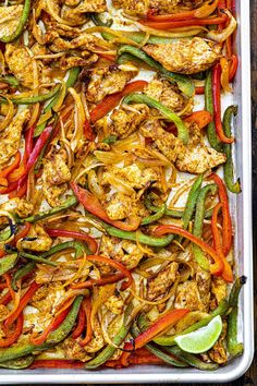 chicken fajita casserole with peppers, onions, and limes on a baking sheet