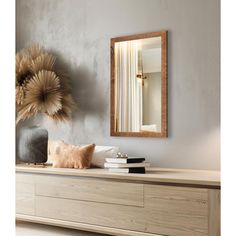 a large mirror on the wall above a dresser with books and pillows in front of it