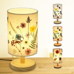 a lamp with flowers on it sitting on a table next to four different shades of lamps