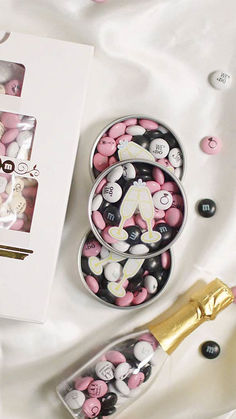 a couple of pink and white candies in a box next to a champagne bottle