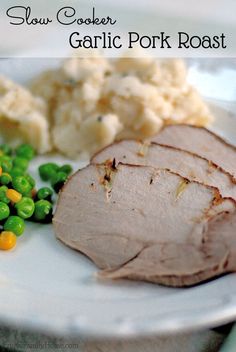 slow cooker garlic pork roast on a plate with peas and mashed potatoes