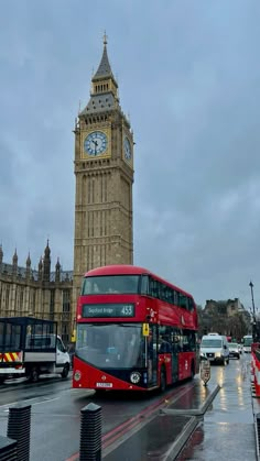 a red double decker bus driving past big ben