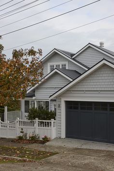 a house with two garages and a white picket fence