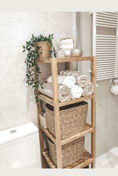 a wooden shelf with baskets and towels on it next to a toilet in a bathroom