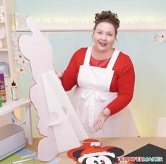 a woman in an apron holding up a paper cutout