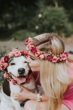 a woman is hugging her dog with flowers in her hair and wearing a flower crown