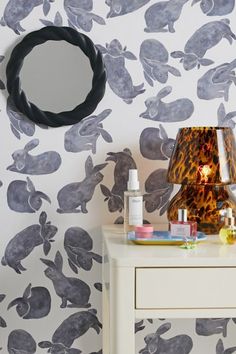 an animal print wallpaper with a lamp and mirror on the table next to it