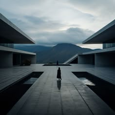 a person standing in the middle of an empty pool with mountains in the background at dusk